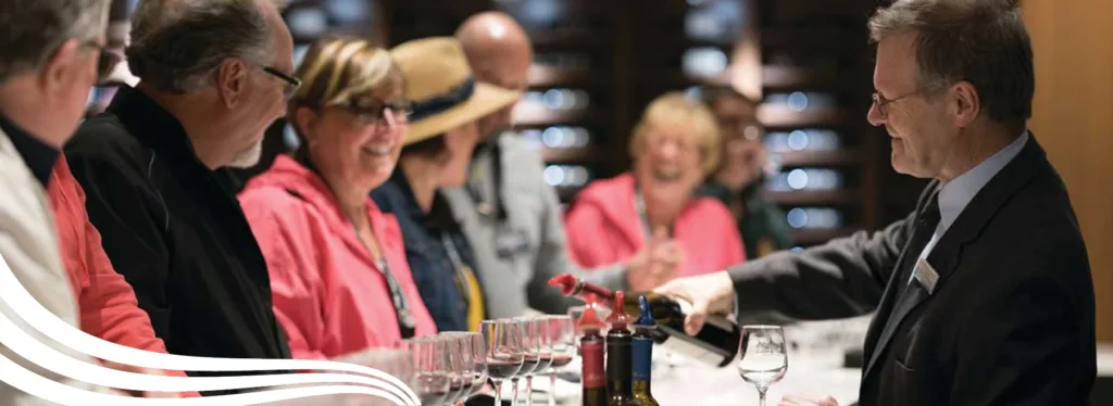 Tour group enjoying a wine tasting as a sommelier pours wine at a winery cellar