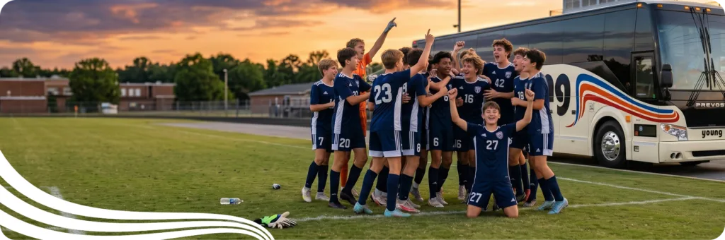 Youth soccer team celebrating on the field beside a Young Transportation motorcoach at sunset