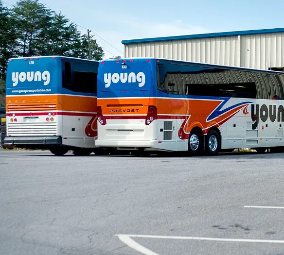 Three Young Transportation Prevost motorcoaches parked outside depot with orange and blue livery