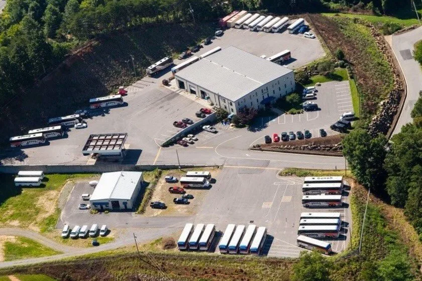 Aerial view of Young Transportation fleet depot with motorcoaches and vans parked around a large facility building