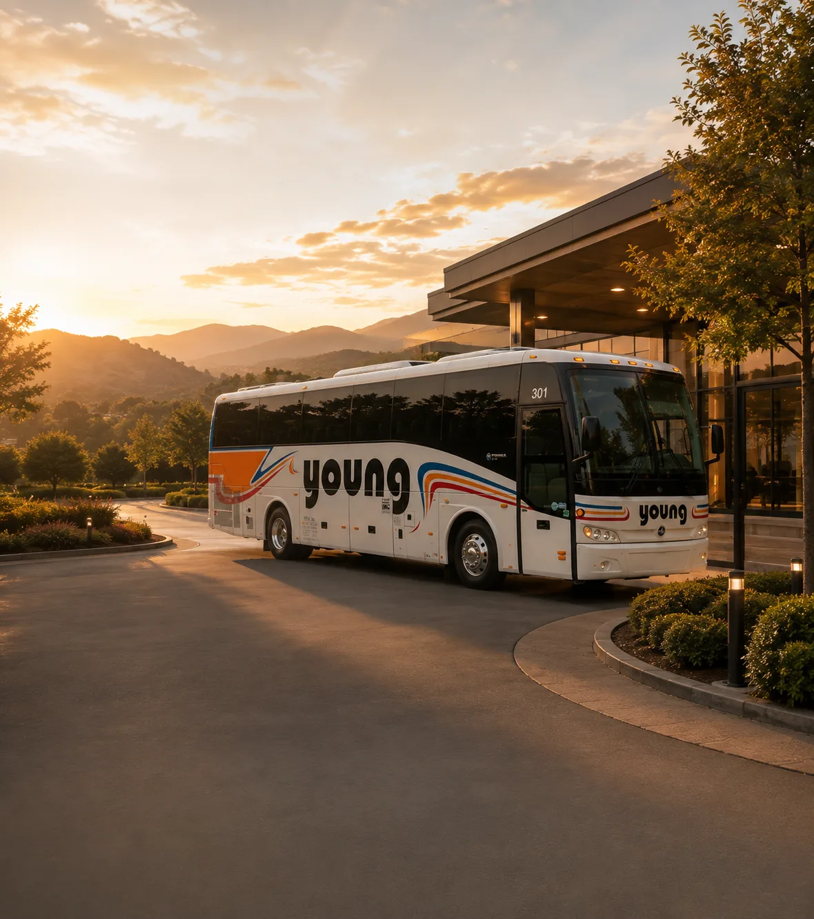 Young Transportation motorcoach parked at a hotel entrance at sunset with mountain views in the background