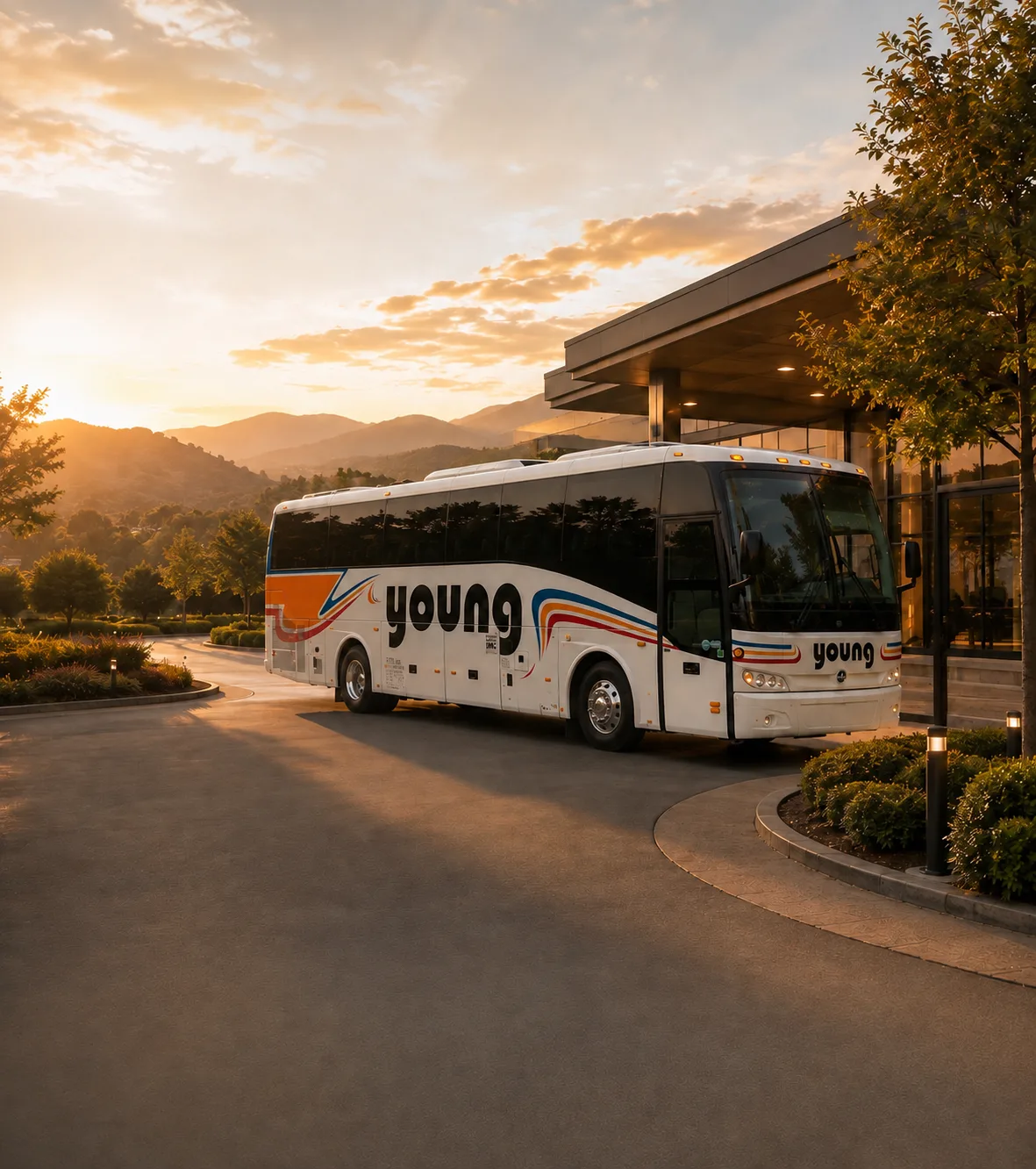 Young Transportation motorcoach parked at a hotel entrance at sunset with mountain views in the background