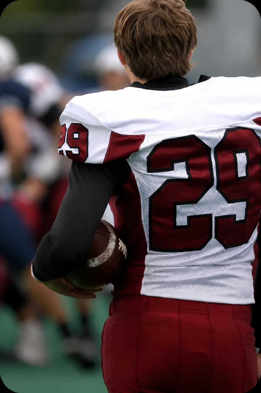 Football player in jersey number 29 holding a football on the sideline